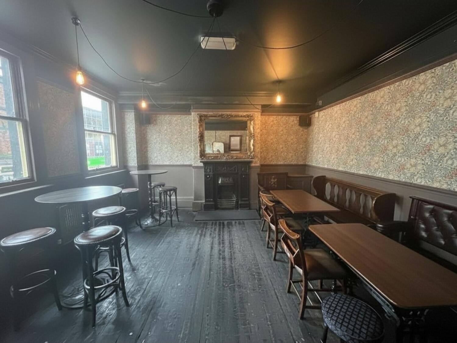 From door facing right. High tables and stools on left wall. Half booth, table and chairs on the right wall.