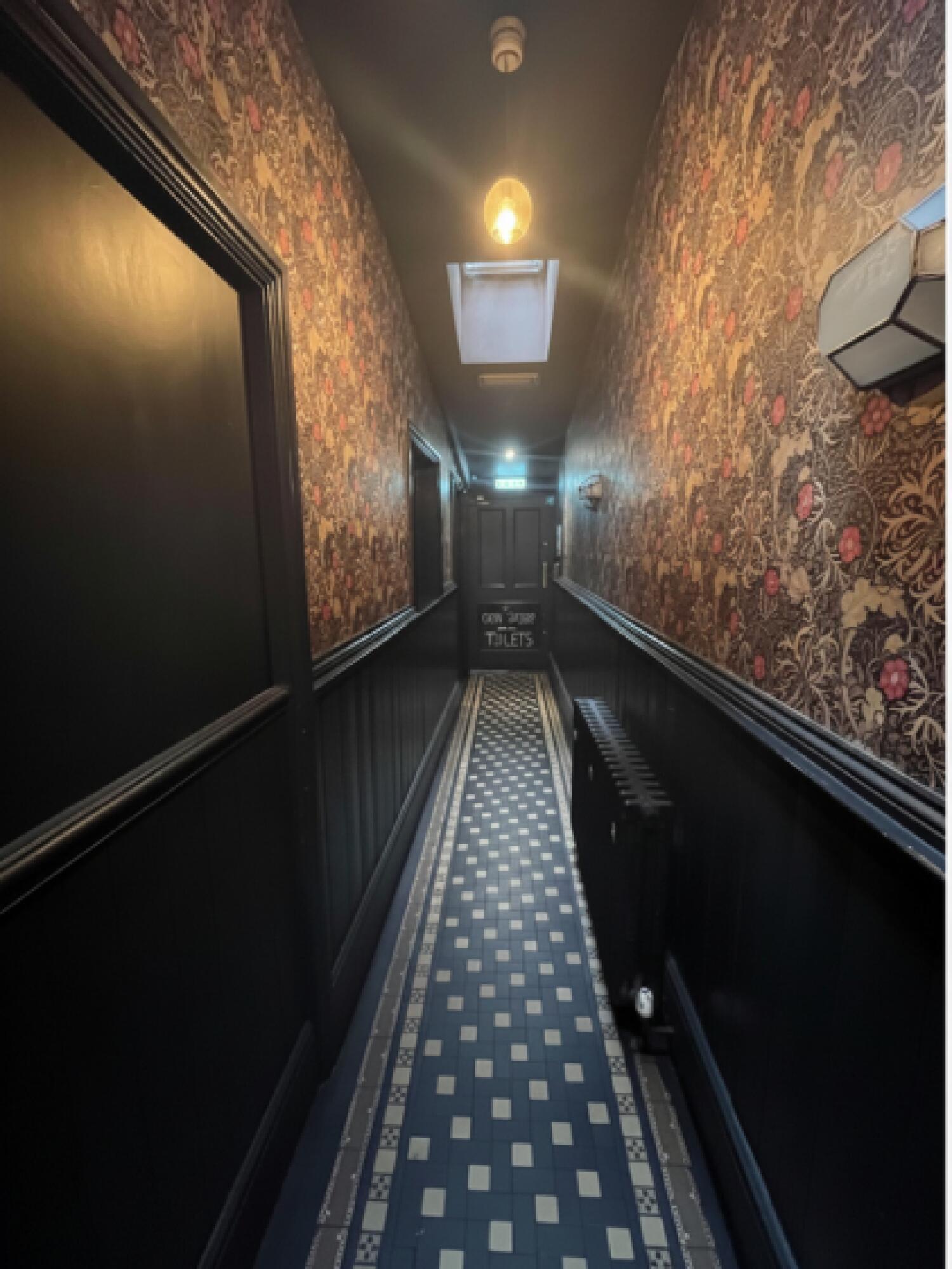 From door facing straight. Path down center to door to outdoors at back and bathroom door on left wall.