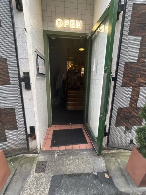 Glass door with green frame, metal handle on left. Pull to open.