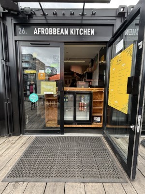 Double glass door with black doorframe. Handle in the centre. Pull from right door to open. Rubber mat before doorway.