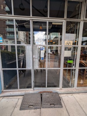 White frame doors. Push to open. Small step at entrance. Rubber ramp to entrance.