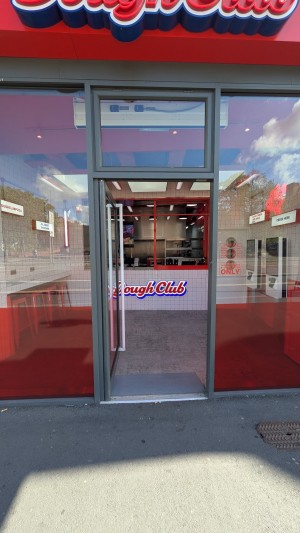 Glass door with metal frame. Push white handle on right to open