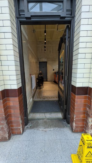Glass door with wooden frame. Push metal handle on left to open.
