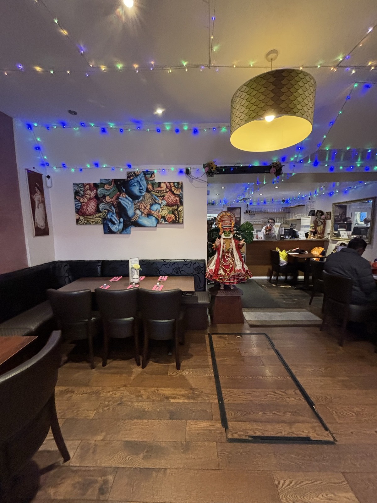 From midsection of front space facing straight. Black half-booths along left and back wall. Decorative elements on ceiling and walls. Tables to right