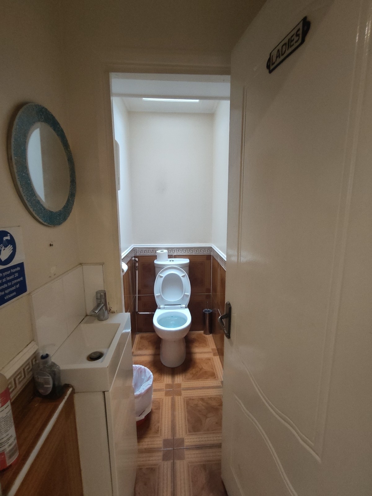 From door facing straight. Sink to the left. Archway at back. Toilet on back wall after archway.