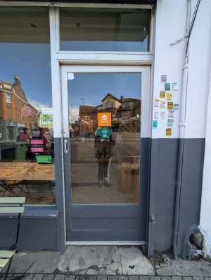 White and grey frame door. Metal handle on left. Push to open. Raised edge at entrance.