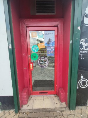 Glass door with red frame. Push handle on left to open.
