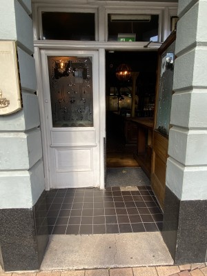 White wooden door with frosted glass paneling. Pull the handle in centre to open towards right.