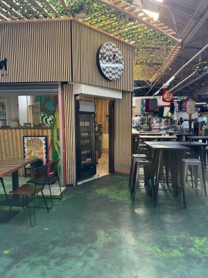 From centre of market path facing venue. Tables and chairs on left and right. Opening to staff area ahead.