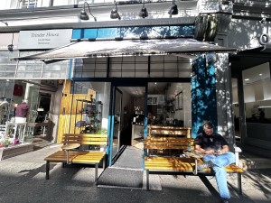 From street, facing venue. Tables and benches on both sides. Doorway at back.