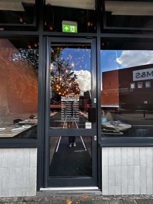 Glass door with black metal frame. Push from black, handle on right to open.