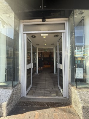 Glass doors. Metal handle in centre. Push in centre to open. Followed by path to archway.