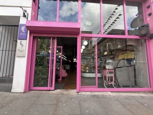 Glass door with pink frame and long pink handle on right. Slide to left to open.