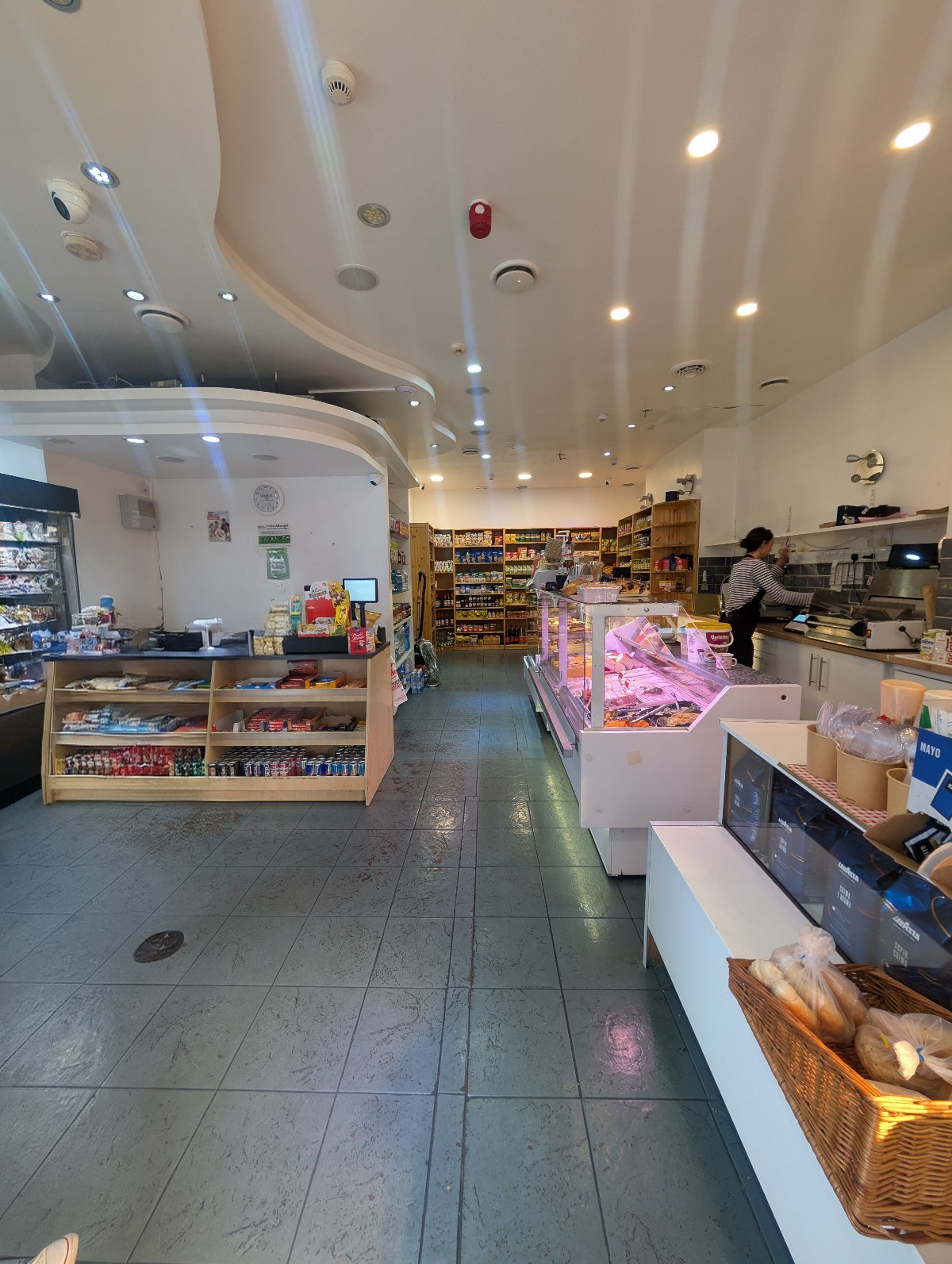From left of deli counter facing straight. Payment counter on left. Path to backspace in center. Deli counter along right.