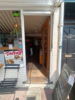 Glass door with brown, wooden frame ahead. Push from silver handle on left to open.