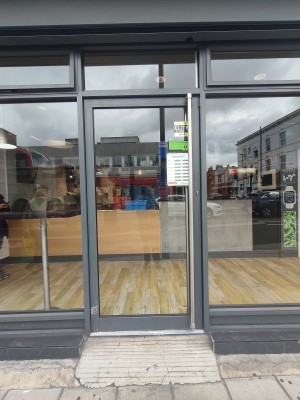 Grey framed glass door ahead. Push silver handle on right to open.