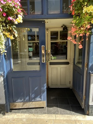 Blue door with glass panelling. Push the golden handle in centre to open.