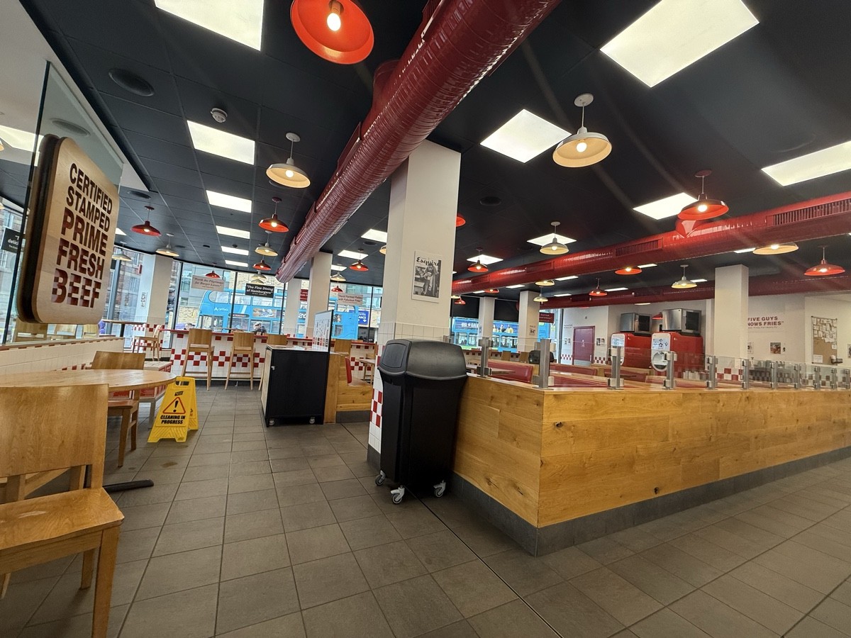 From kiosks facing straight. Tables and chairs on left. Bin central. Booths on right.