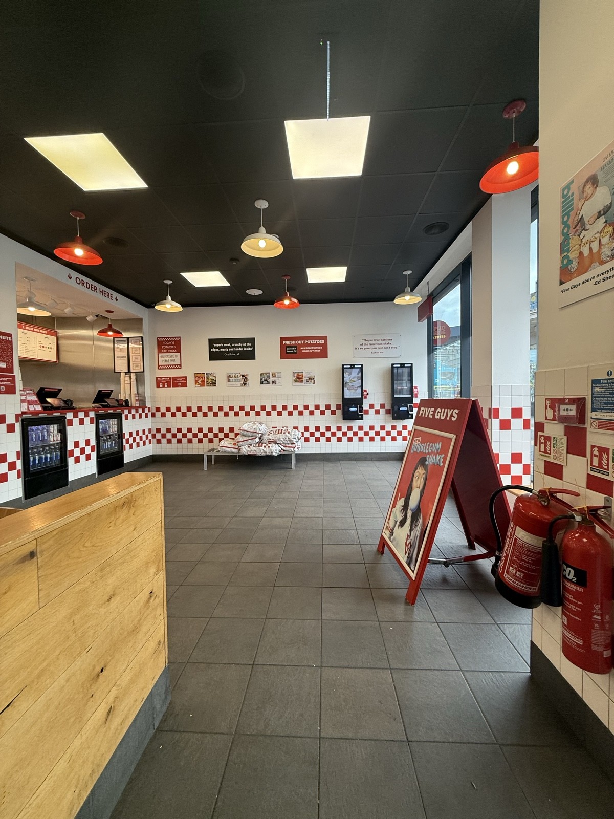 From entrance facing right. A sign on right. Kiosks on right. Path central. Order counter on left.