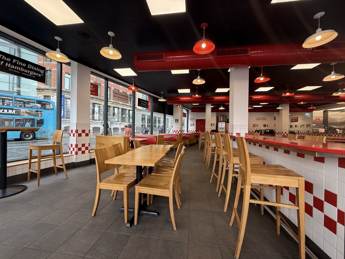 From high tables facing straight. Booths back left. Table and chairs central. High tables and stools on right.