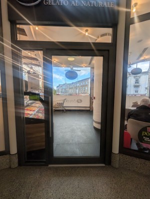 Grey frame door. Metal handle on left. Push to open. Small bump at entrance.