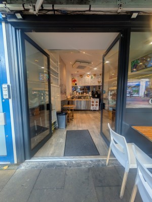 Grey frame doors. Metal bars in center. Push to open. Small bump at entrance. Doormat after.