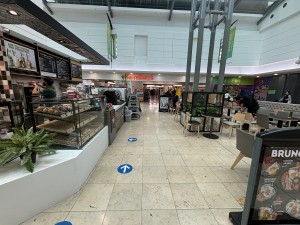 From one side of mall facing the venue. Counter and display counter on left. Seating on right and back.
