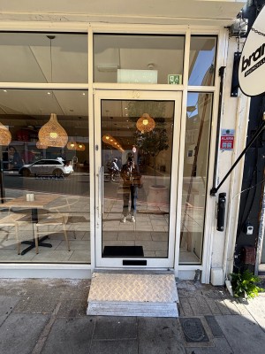 Glass door with white frame ahead. Pull door to open via metal handle on left.