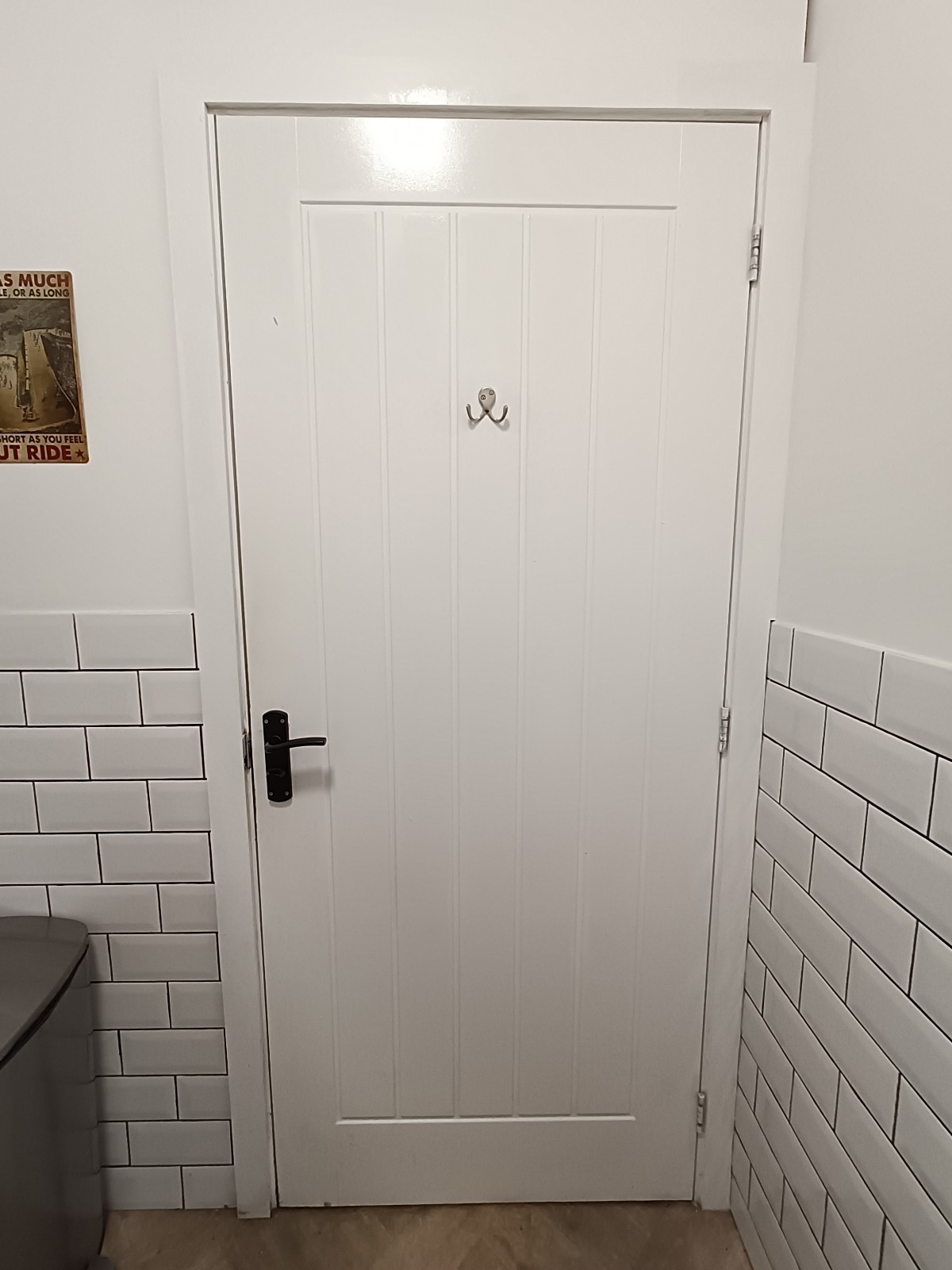 Back of bathroom door. Black handle and lock on left. Pull to open. High hooks on top.