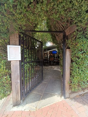 Black, metal gate ahead. Push from right to open.