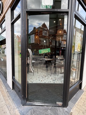 Glass door with black frame ahead. Metal handle on left. Push to open.