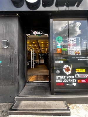 From sidewalk facing door. Open archway ahead.