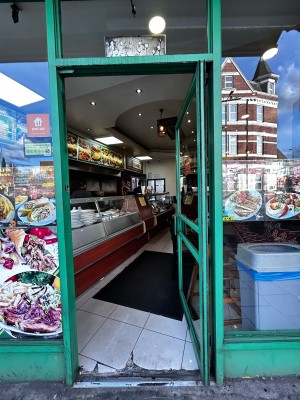 Glass door with green frames. Push pad on the left. Push to open.