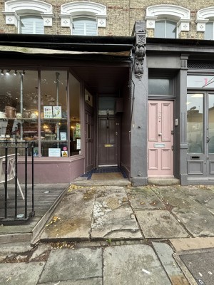 From sidewalk facing straight, entrance to venue to the left. Two different height steps leading to main door. Large glass windows to the left