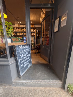 Grey frame door in front. Metal pad on left. Push to open. A sign on left.