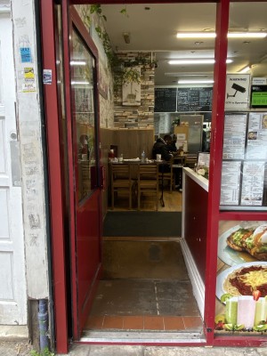 Red framed door with glass panelling. Push the red handle on right to open.