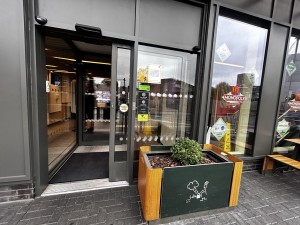 Glass doors with dark green metal frames on left. Planter on the right.