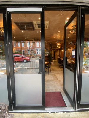 Black framed glass door with black metal handle in centre. Push the door from centre to open.