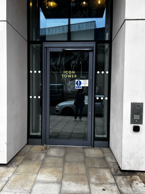 From sidewalk facing venue. Archway ahead. Door in center. A concierge button on the right side of archway.