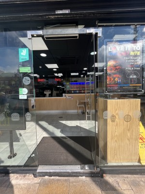 Glass door with handle on left. Push to open.
