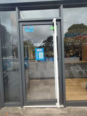 From sidewalk facing venue. Black framed door ahead. Push white handle on right to open.