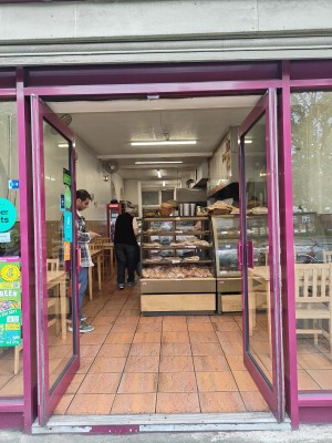 Facing venue entrance. Pink framed glass doors in front. Push pink bar in centre to open.