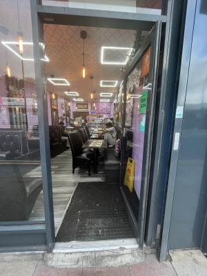 Glass door with grey frame. Handle on left. Push to open