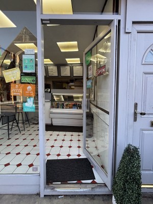 Glass door with white door frame, door handle to the left, push to open. Glass door to the left.