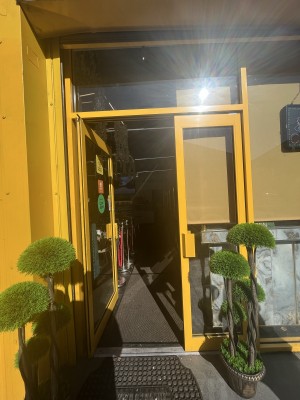Glass door with yellow metal frame. Push handle on right to open.