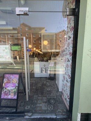 Glass door with metal handle on left. Push to open.