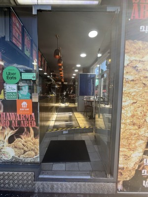 Glass door with a metal handle on left. Push to open.