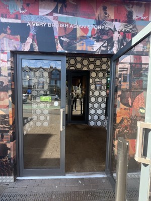 Glass double door with grey frame. Metal handle in centre. Pull to open.