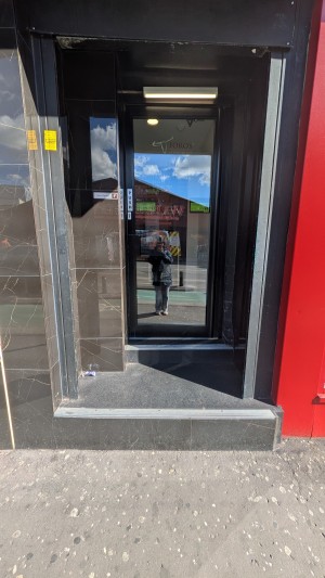 Glass door with black frame. Push metal handle on left to open