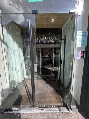 Glass double door with a black handle in centre. Push to open.